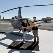 Newly certificated pilot with instructor beside the helicopter